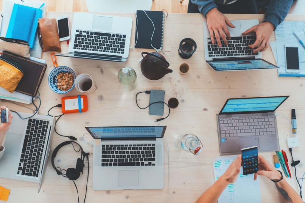 Grupo diverso de profissionais colaborando alegremente em uma mesa de trabalho, representando fit cultural e sinergia organizacional.