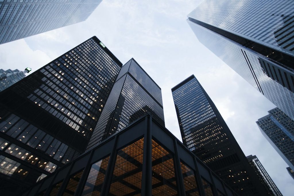Um imponente edifício corporativo com fachada espelhada refletindo o céu, simbolizando governança corporativa e sucessão de C-Level.