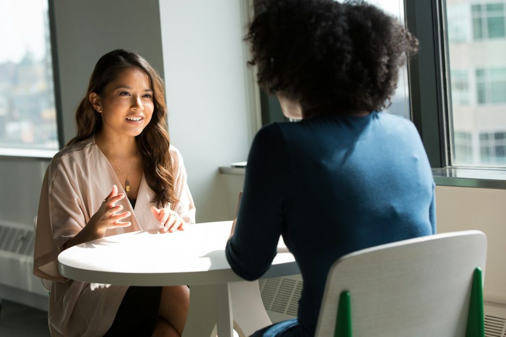 Duas profissionais conversando em entrevista de emprego num escritório